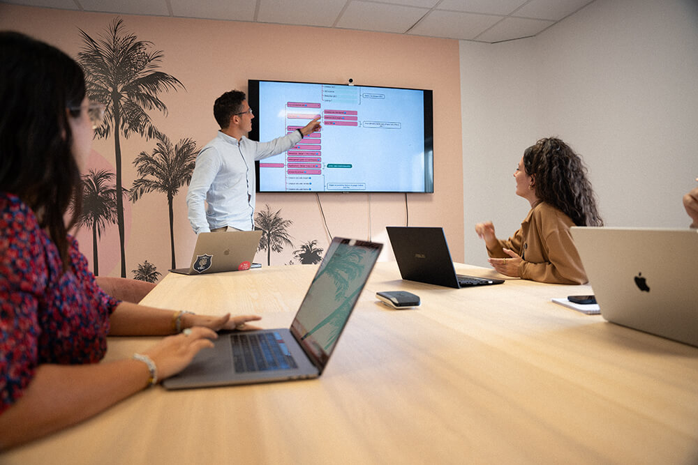 4 collaborateurs (idéalement 1 inté + cdp + seo + dir cli) en salle de réu devant wireframe ou arbo ZKO affiché à l'écran