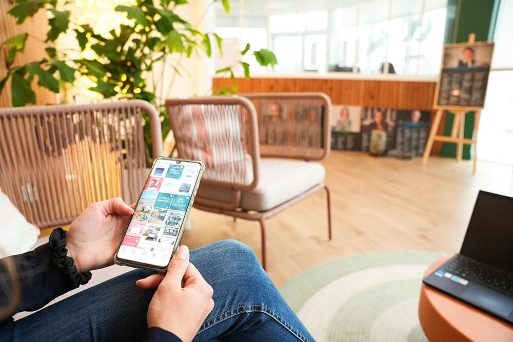 Jessica sur un pouf rose en train de regarder Pinterest sur son téléphone, prise de vue de face/côté